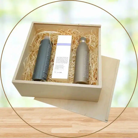 Ein hölzerner Geschenkkarton, gefüllt mit Stroh und drei Kosmetikflaschen.