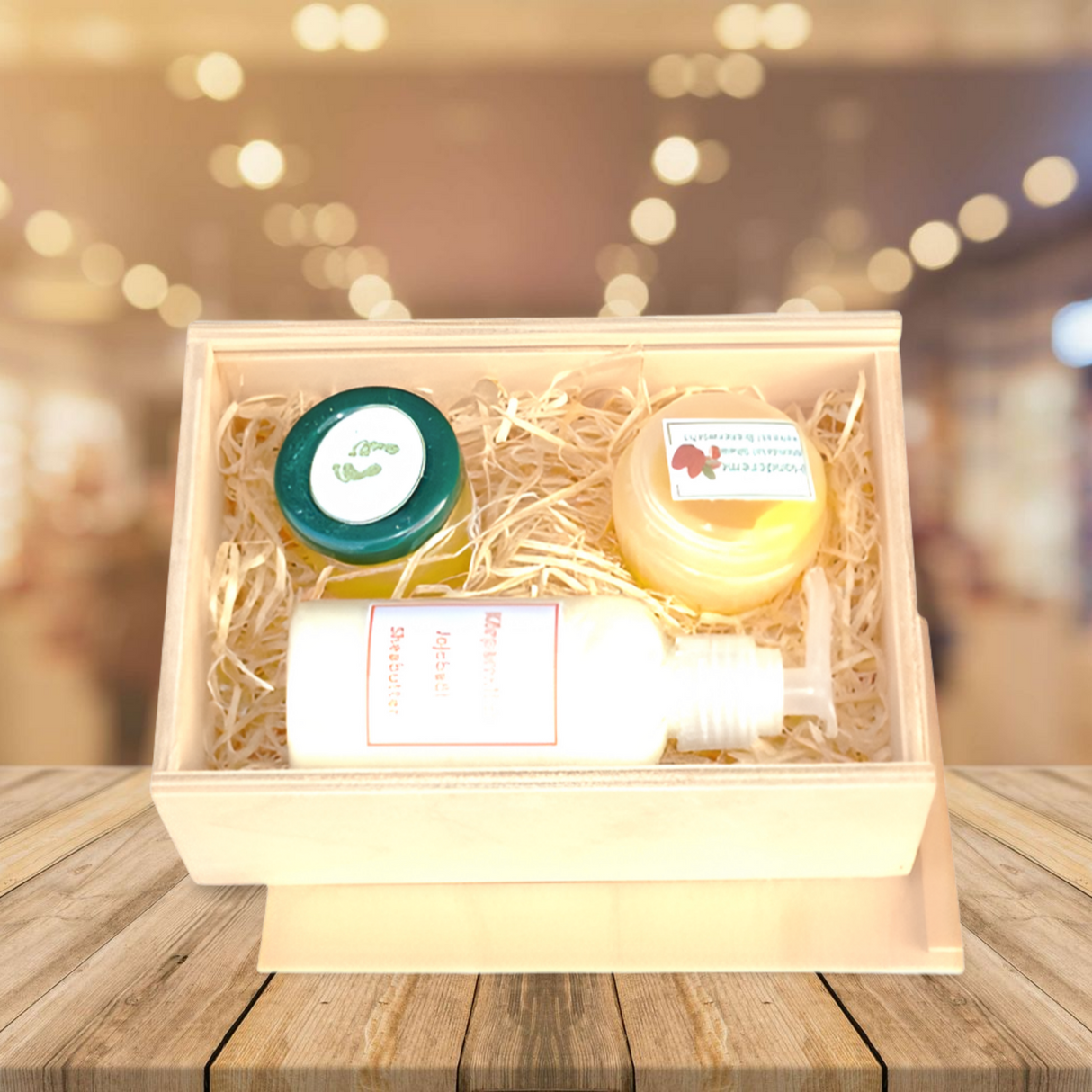 Geschenkbox aus Holz mit Naturfaserauskleidung, die eine weiße Flasche und zwei runde Behälter in Grün und Gold enthält.