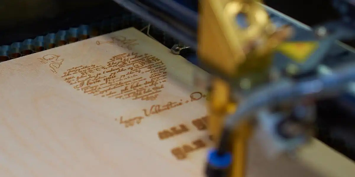 Ein Lasergravierer graviert präzise ein Design auf eine hellfarbige Holzoberfläche.