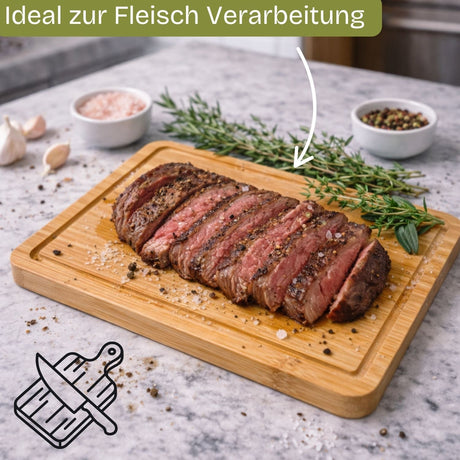 Dünn geschnittenes medium-rare Steak liegt auf einem hellen Bambusschneidebrett und ist mit grobem Salz und schwarzem Pfeffer gewürzt.