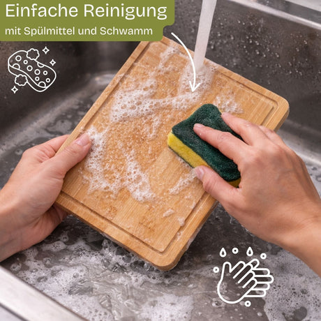 Ein rechteckiges Bambusschneidebrett mit natürlicher Holzmaserung, das unter fließendem Wasser gewaschen wird.