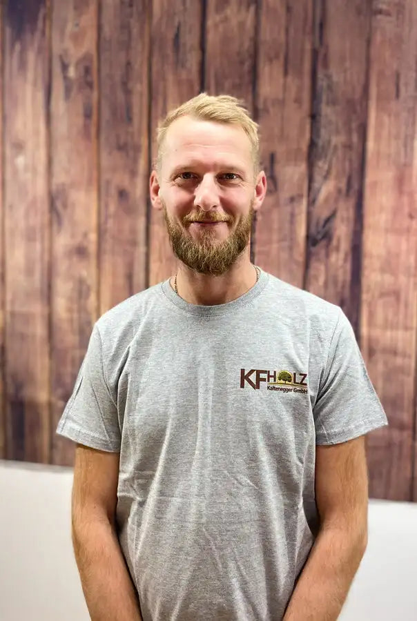 Graues kurzärmeliges T-Shirt mit einem braunen Logo auf der linken Brust, das ’kfholz’ und ein Eichenbaum-Symbol zeigt