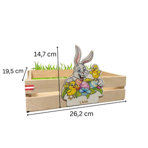 Hellfarbenes, holzernes Ostern-Themen-Blumentopf mit einem Cartoon-Hasen- und Küken-Design, das bunte Eier, grünes Gras innen und den Namen »lara« auf der Vorderseite zeigt.