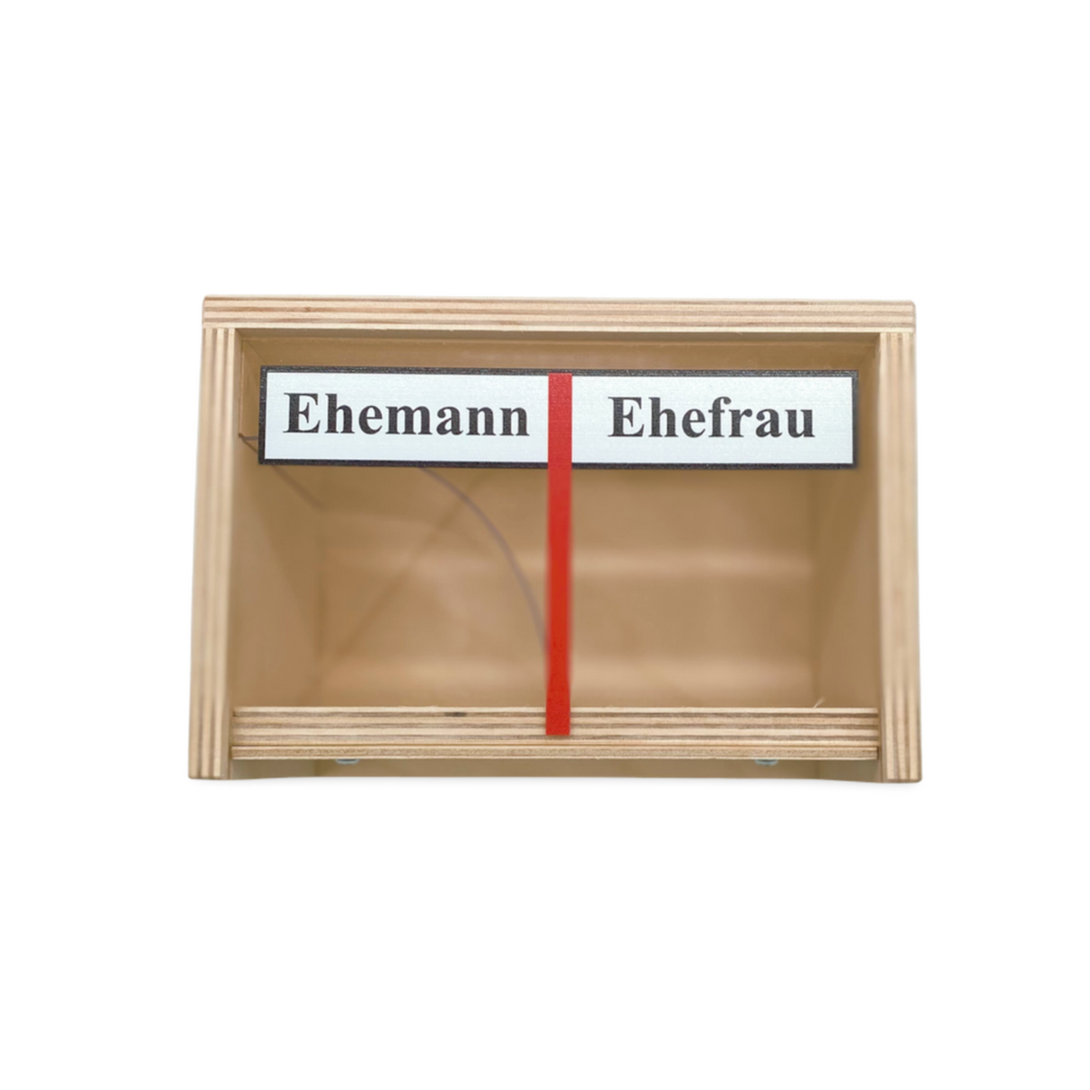 Eine Holzkiste mit zwei Fächern, die mit ’Ehemann’ und ’Ehefrau’ beschriftet und durch eine rote Trennwand getrennt sind.